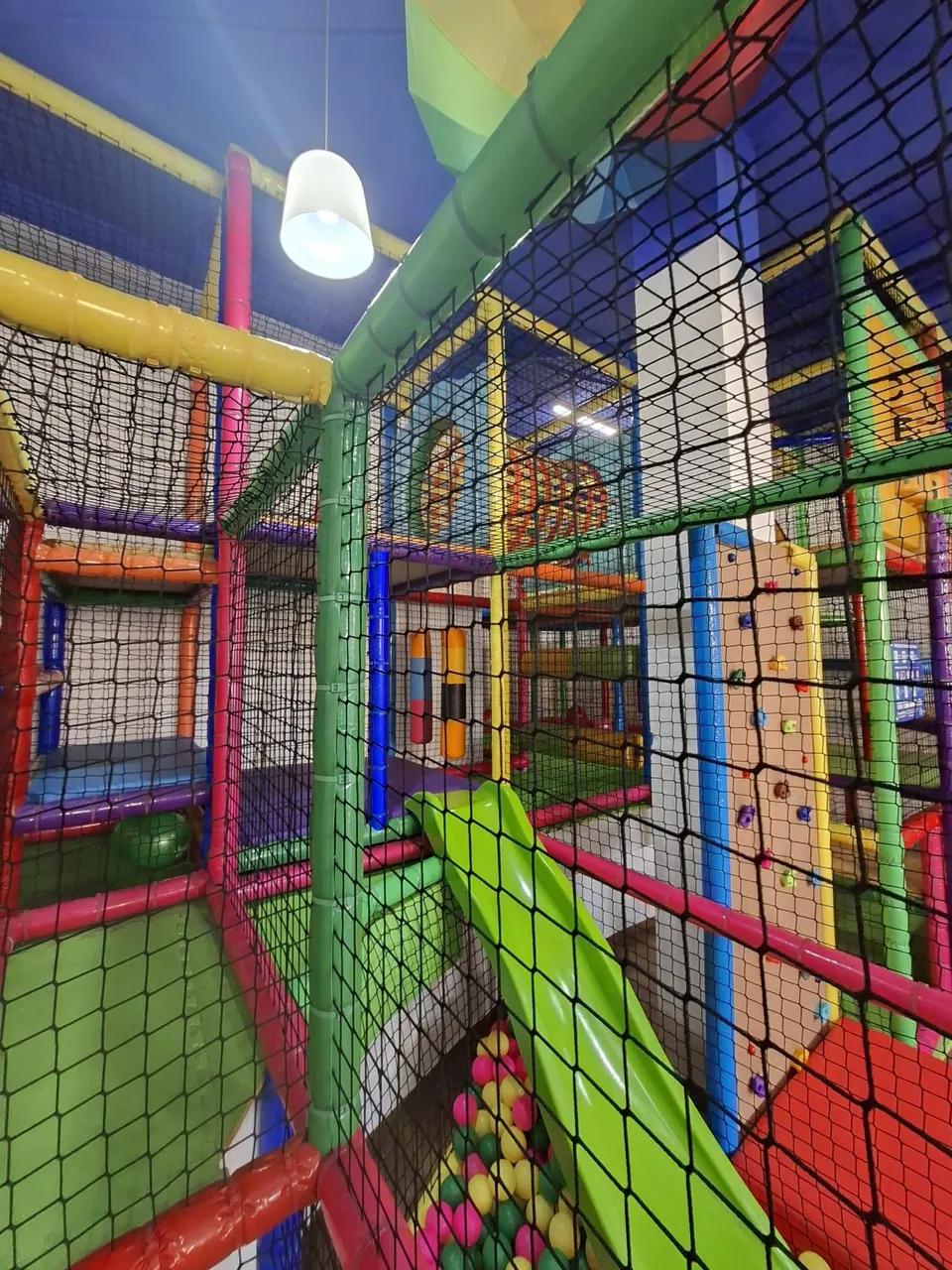 Por dentro del parque de bolas: redes, tubos de colores, el tobogán verde y la piscina de bolas